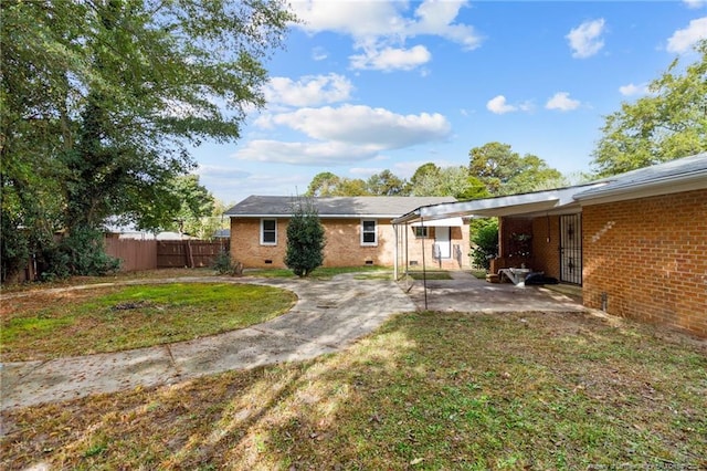 back of property featuring a carport and a lawn