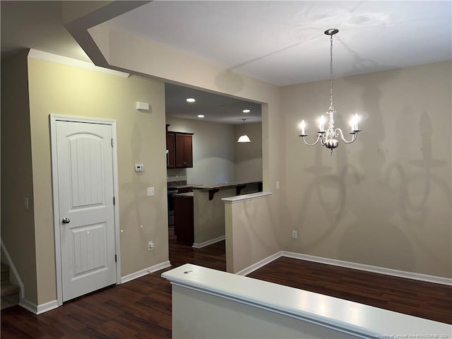 kitchen with decorative light fixtures, dark hardwood / wood-style floors, a notable chandelier, kitchen peninsula, and a breakfast bar area