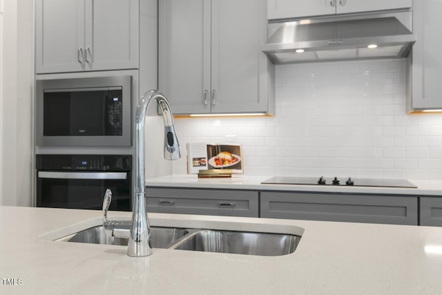 kitchen featuring appliances with stainless steel finishes, decorative backsplash, sink, and exhaust hood