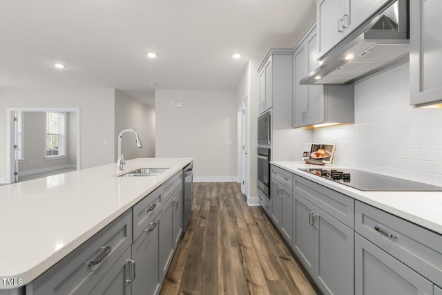 kitchen featuring decorative backsplash, appliances with stainless steel finishes, gray cabinetry, sink, and dark hardwood / wood-style floors