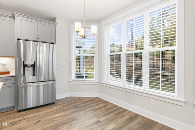 kitchen with decorative backsplash, gray cabinets, wood-type flooring, and stainless steel fridge with ice dispenser