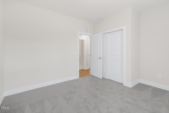 unfurnished bedroom with light carpet and a closet