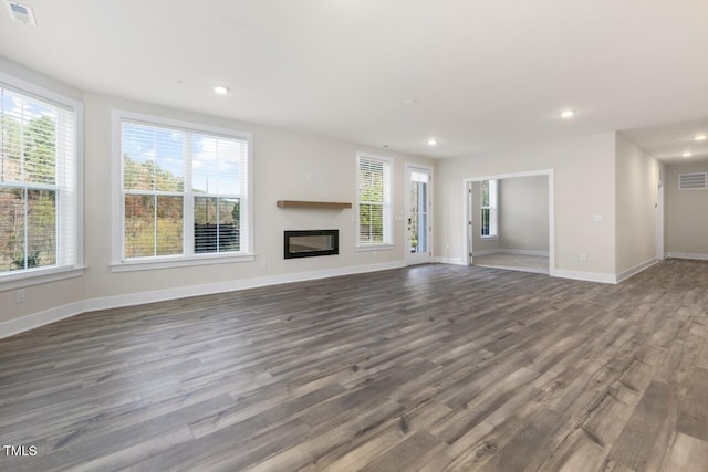 unfurnished living room featuring a wealth of natural light and dark wood-type flooring