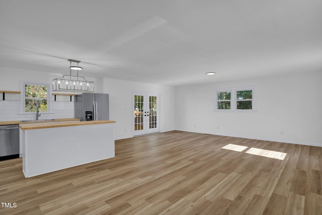 interior space with plenty of natural light, light hardwood / wood-style floors, appliances with stainless steel finishes, and wooden counters