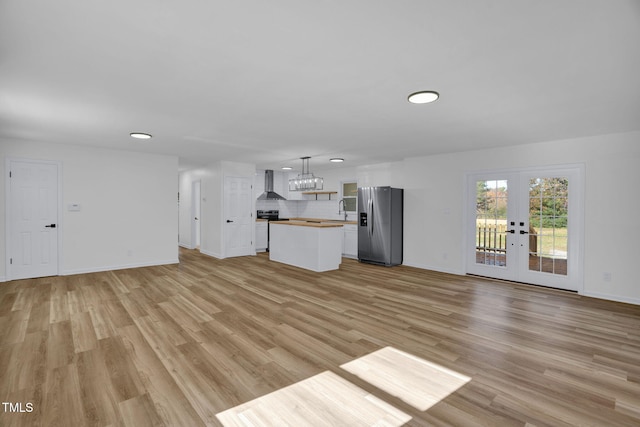 unfurnished living room featuring french doors, light hardwood / wood-style flooring, and sink