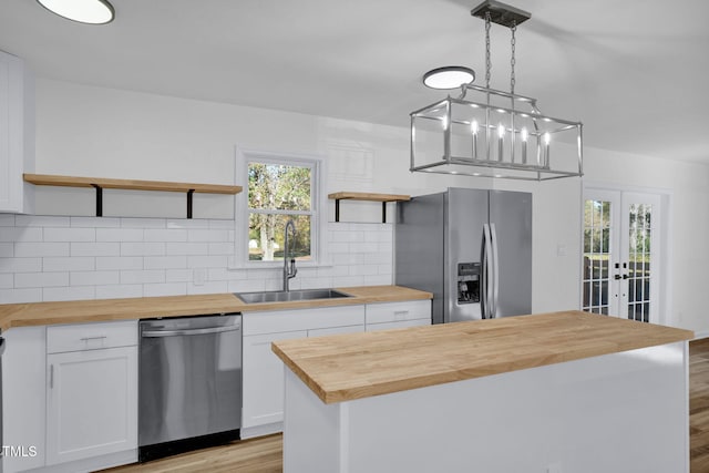 kitchen with pendant lighting, white cabinets, butcher block countertops, a kitchen island, and stainless steel appliances