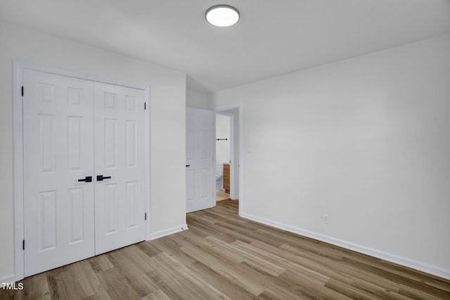 unfurnished bedroom with light wood-type flooring and a closet