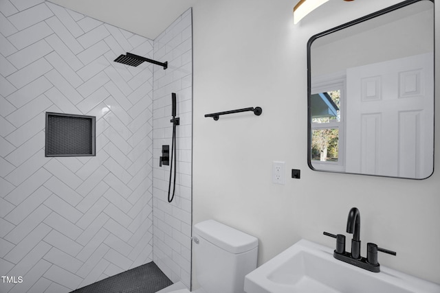 bathroom featuring toilet, sink, and a tile shower