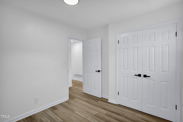 unfurnished bedroom with a closet and light hardwood / wood-style flooring