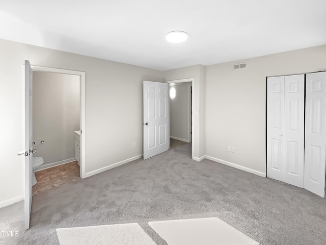 unfurnished bedroom featuring light carpet and a closet