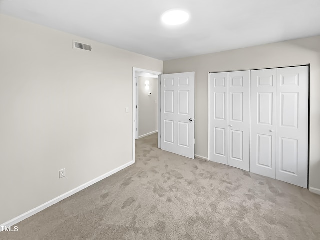 unfurnished bedroom featuring light carpet and a closet