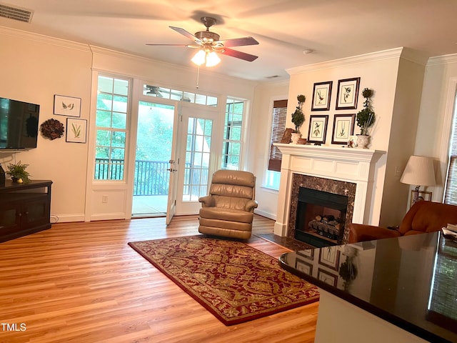 living room with ceiling fan, crown molding, a healthy amount of sunlight, and light wood-type flooring