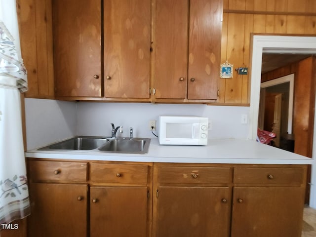 kitchen featuring wooden walls and sink