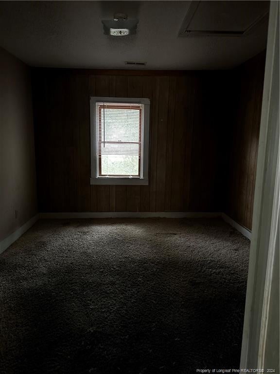 carpeted empty room with wood walls