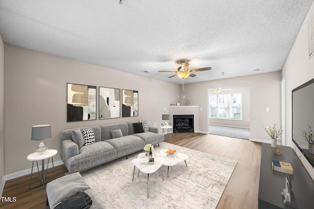 living room featuring ceiling fan, wood-type flooring, and a textured ceiling