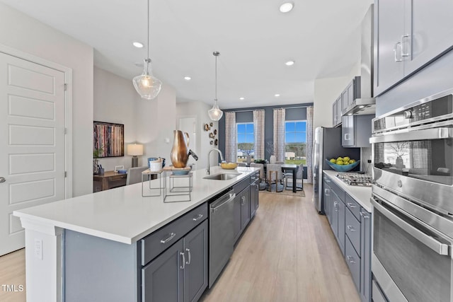 kitchen with a center island with sink, gray cabinets, stainless steel appliances, and sink