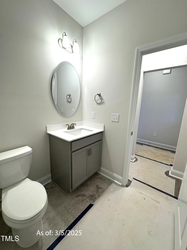 half bathroom with toilet, vanity, and baseboards