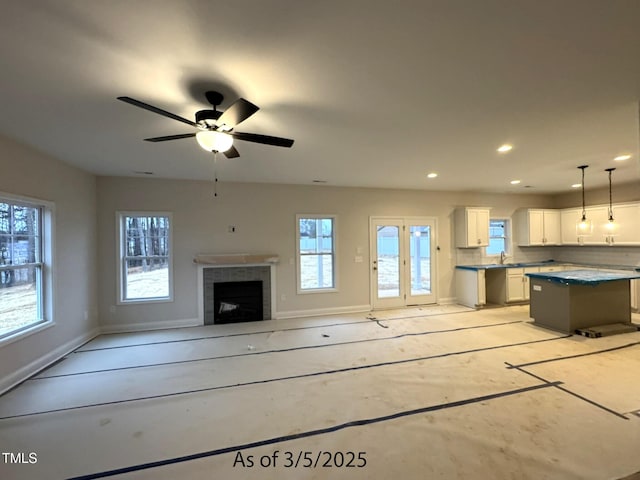 unfurnished living room with baseboards, ceiling fan, a tile fireplace, and recessed lighting