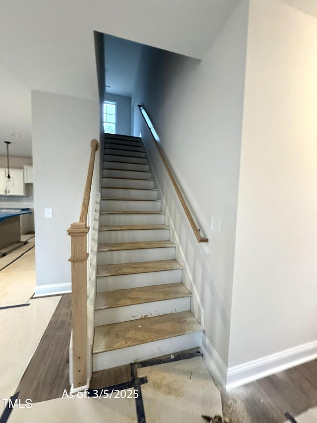 stairway featuring wood finished floors and baseboards