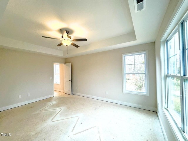 spare room featuring ceiling fan, a raised ceiling, visible vents, and baseboards