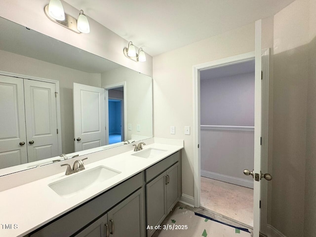 bathroom featuring double vanity, a sink, and baseboards