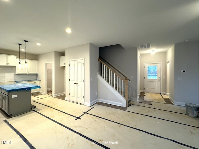 kitchen featuring white cabinets, backsplash, visible vents, and baseboards