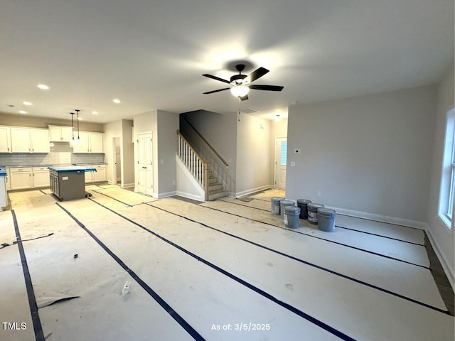 unfurnished living room featuring ceiling fan, stairway, recessed lighting, and baseboards