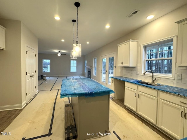 kitchen with a sink, dark countertops, a kitchen island, and decorative backsplash