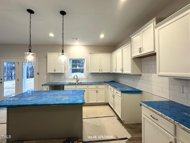 kitchen with a center island, white cabinets, a sink, and backsplash