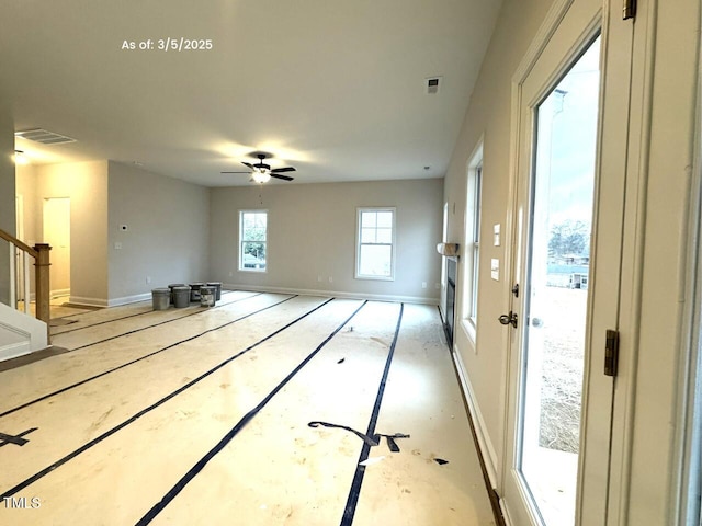 empty room with a ceiling fan, visible vents, stairway, and baseboards