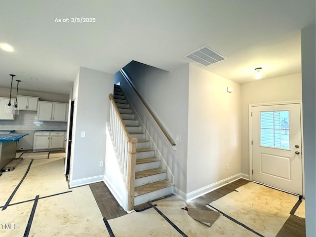 entrance foyer with stairway, baseboards, visible vents, and wood finished floors