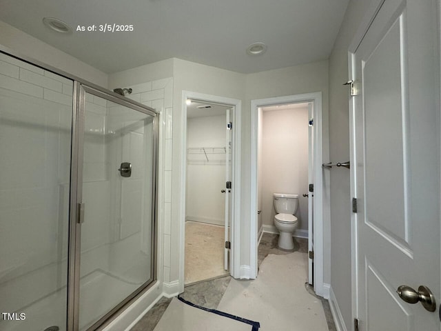 full bathroom with a stall shower, baseboards, a spacious closet, and toilet