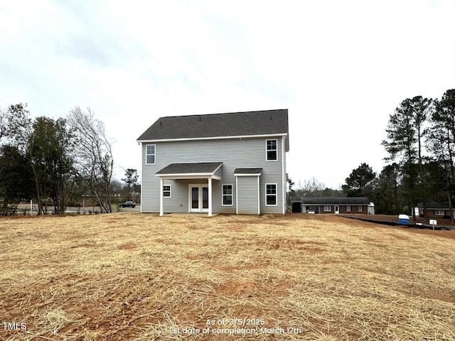 back of property with a lawn and french doors