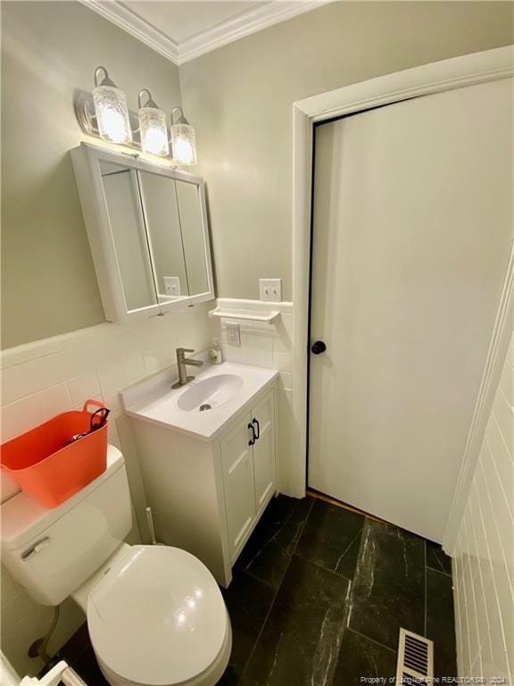 bathroom with crown molding, vanity, tile walls, and toilet