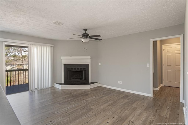 unfurnished living room featuring a fireplace with raised hearth, wood finished floors, visible vents, and baseboards