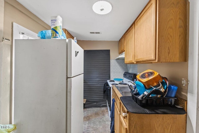 kitchen with white refrigerator, range with electric cooktop, and backsplash