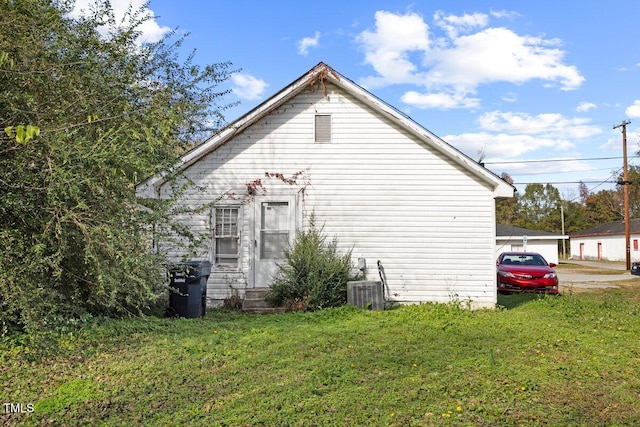 view of side of property with central AC unit and a lawn