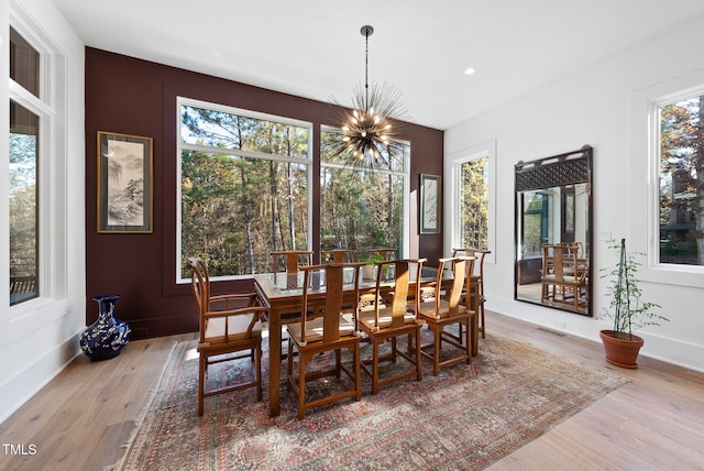 dining space with a notable chandelier, plenty of natural light, and light hardwood / wood-style flooring