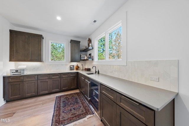 kitchen featuring dark brown cabinets, light hardwood / wood-style flooring, wine cooler, and sink