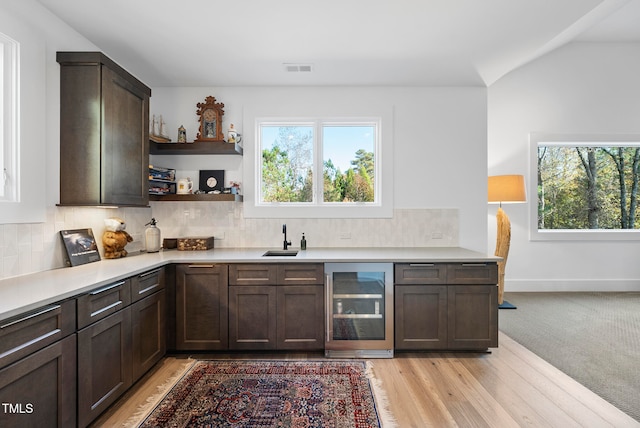 kitchen featuring plenty of natural light, decorative backsplash, light wood-type flooring, and wine cooler