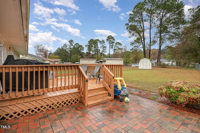 wooden terrace featuring a yard, a patio, and a storage unit