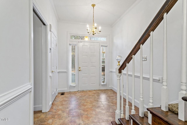 entrance foyer with crown molding, a textured ceiling, and an inviting chandelier