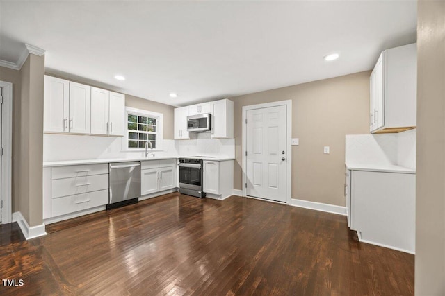 kitchen with white cabinetry, ornamental molding, dark wood-type flooring, and appliances with stainless steel finishes