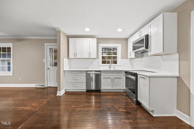 kitchen with appliances with stainless steel finishes, dark hardwood / wood-style flooring, ornamental molding, sink, and white cabinets