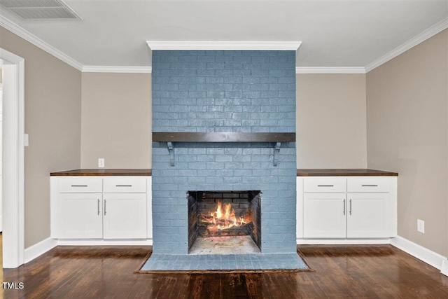 unfurnished living room with a brick fireplace, dark hardwood / wood-style flooring, and ornamental molding