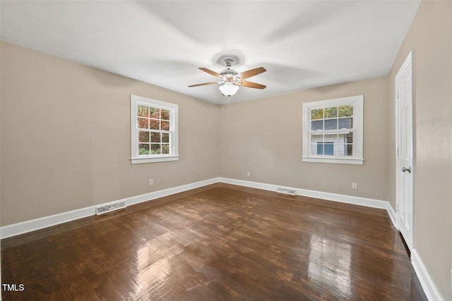 spare room with a wealth of natural light, ceiling fan, and dark wood-type flooring