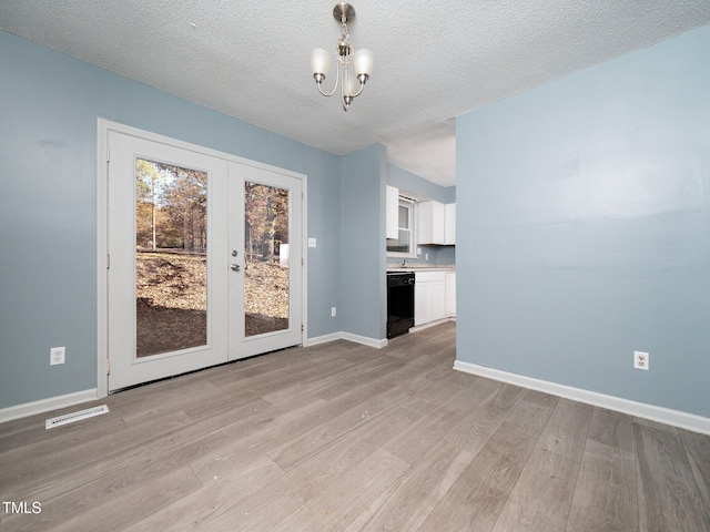 unfurnished dining area featuring light hardwood / wood-style floors, a textured ceiling, and french doors