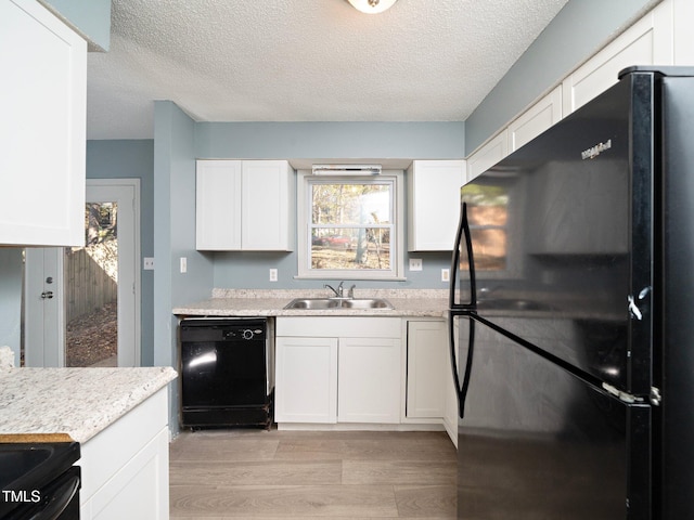 kitchen with white cabinetry, sink, black appliances, and light hardwood / wood-style floors