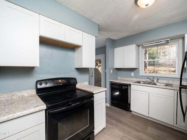 kitchen featuring sink, wood-type flooring, a textured ceiling, white cabinets, and black appliances