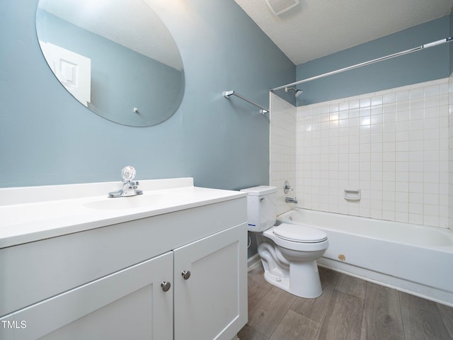 full bathroom with wood-type flooring, a textured ceiling, toilet, vanity, and tiled shower / bath